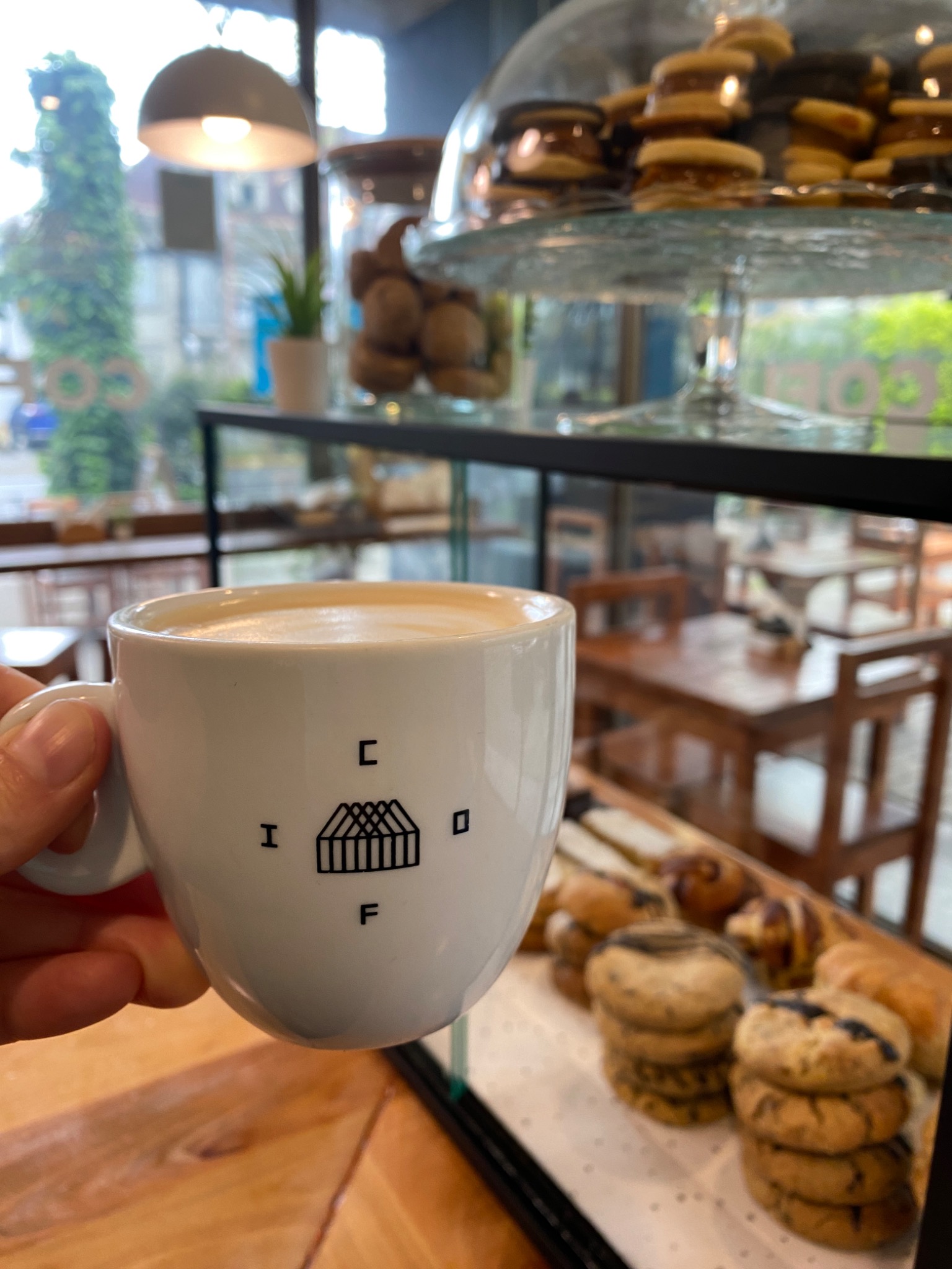 Taza COFI frente a la vitrina de pastelería